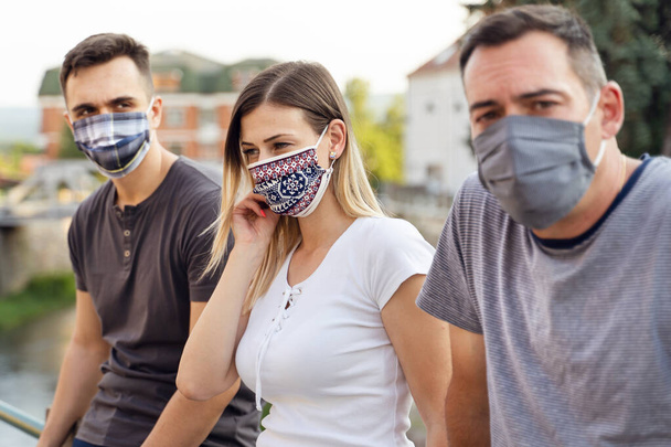 Группа кавказских туристов-миллениалов в отпуске в защитных масках - социальная дистанция и предосторожность в связи с пандемией ковид-19 - кавказские друзья закрывают новую концепцию нормального образа жизни
 - Фото, изображение
