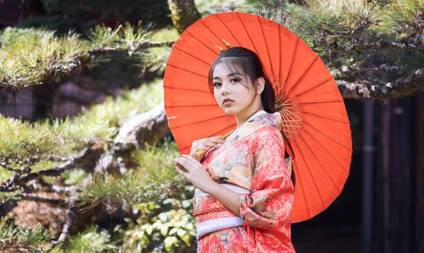 Turista asiatica. Ragazza giapponese con un kimono con un ombrello rosso in mano. Bella ragazza che indossa il tradizionale kimono giapponese a Tsumago juku è ora popolare nel villaggio di Nagano Prefettura, Giappone. - Foto, immagini