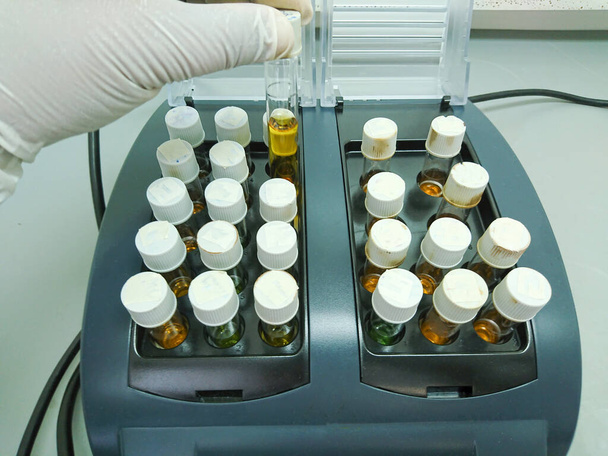Wetenschapper plaatst een reageerbuis in een warmteblok, Chemische zuurstofbehoefte, Afvalwateranalyse. - Foto, afbeelding