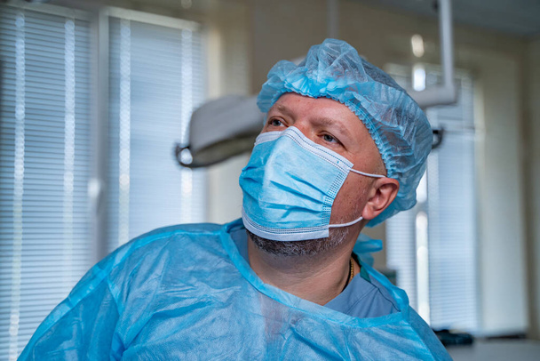 Doctor in medical room. Medical worker looking at side. Man in medical mask and hat. Medical concept. - Foto, Imagen