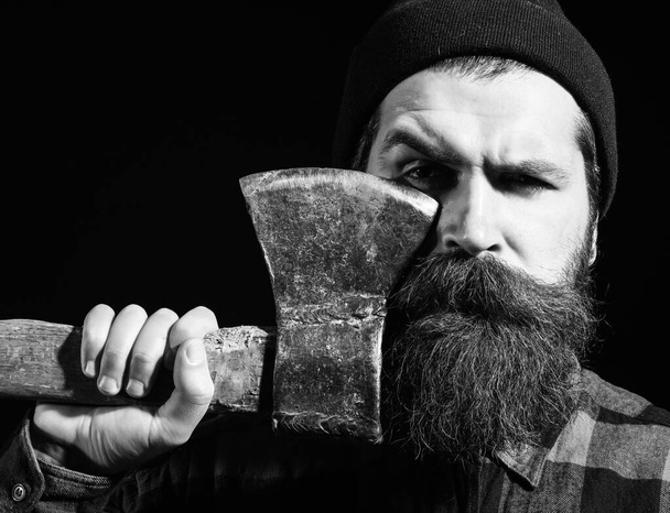 Handsome bearded man in hat holds axe on black background - Фото, изображение
