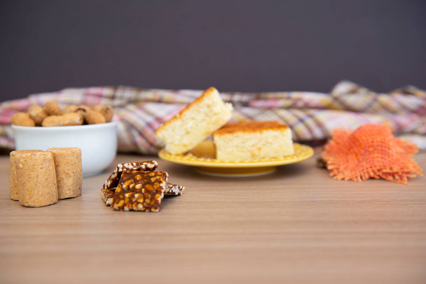 Типові партійні страви на дерев'яному столі: кукурудзяний торт, арахісові горіхи, арахісові цукерки (п-де-молюска) та маленькі заміські капелюхи. Копіювати простір. Вибірковий фокус
. - Фото, зображення
