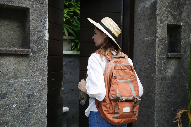 Turist kadın yaz tatilinde hasır şapka ve turuncu sırt çantası takıyor.. - Fotoğraf, Görsel