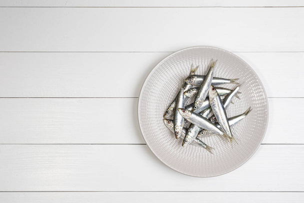some sardines arranged on a plate on the white wooden table - Φωτογραφία, εικόνα