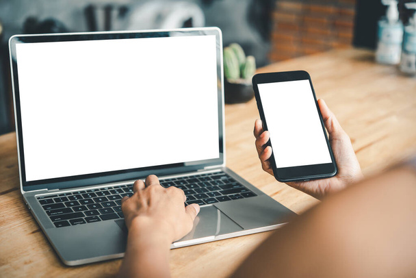 imagem mockup da mão de uma mulher trabalhando em um laptop e telefone inteligente com tela de espaço de cópia de desktop branco em branco em uma mesa
 - Foto, Imagem
