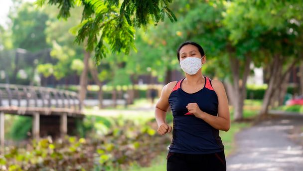 Ritratto di donna asiatica che indossa una maschera facendo jogging nel parco
 - Foto, immagini