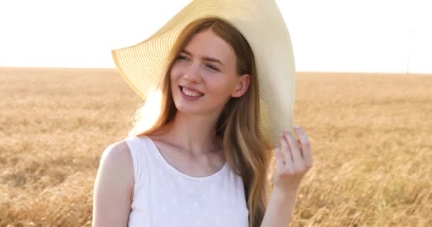 Beautiful happy girl in a straw hat, in a wheat field at sunset - Video