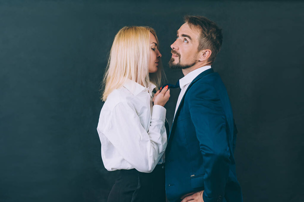 A girl pulls a businessman by a tie on a dark background - Photo, image
