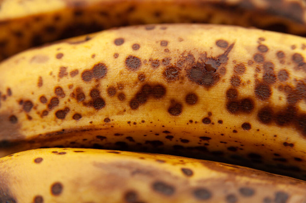 Drie volwassen bananen geïsoleerd op een lichte houten ondergrond. Een close-up. Bovenaanzicht. - Foto, afbeelding