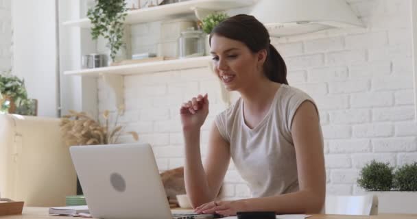 Happy young woman looking at laptop making videocall at home - Footage, Video