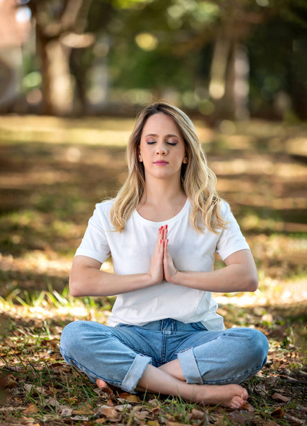 beautiful young woman meditating in park outdoors and under trees. - Photo, Image