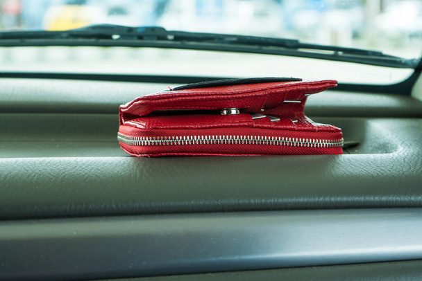 Червоний гаманець залишився на приладовій панелі автомобіля
.  - Фото, зображення