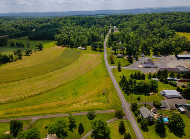 Luftaufnahme aus den Höhen eines ländlichen Dorfes mit Feldern, grünem Gras und Wiesen an einem sonnigen Tag. - Foto, Bild