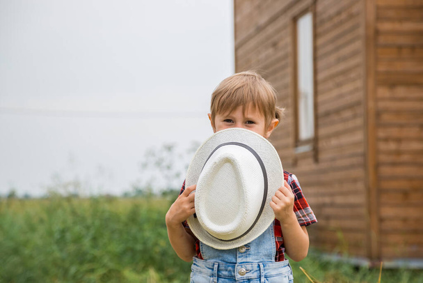Aranyos kislány cowboy kalapban, farmernadrágban és piros fehér ingben.  - Fotó, kép