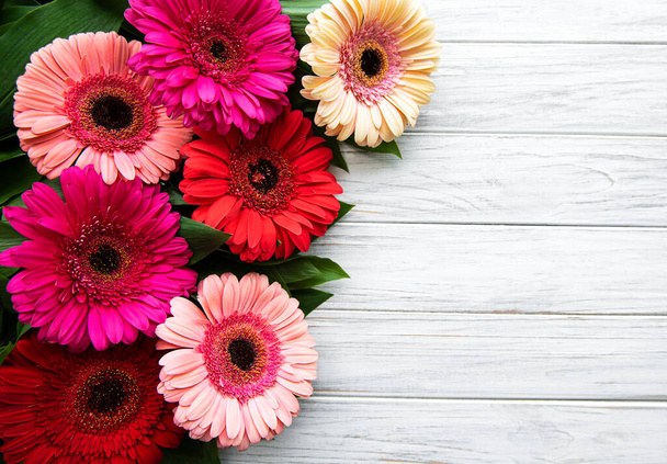 Bright gerbera flowers on a white wooden  background. Frame of flowers, top view - Photo, Image