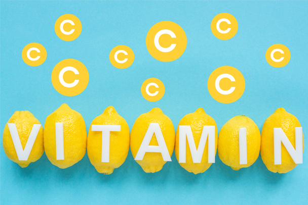 top view of ripe yellow lemons and vitamin C illustration on blue background - Foto, Imagem