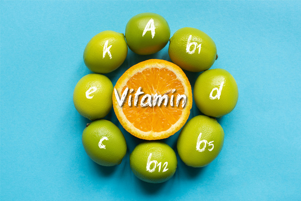 ylhäältä näkymä kypsä oranssi ja limetit järjestetty ympyrän sinisellä pohjalla, vitamiineja kuva - Valokuva, kuva