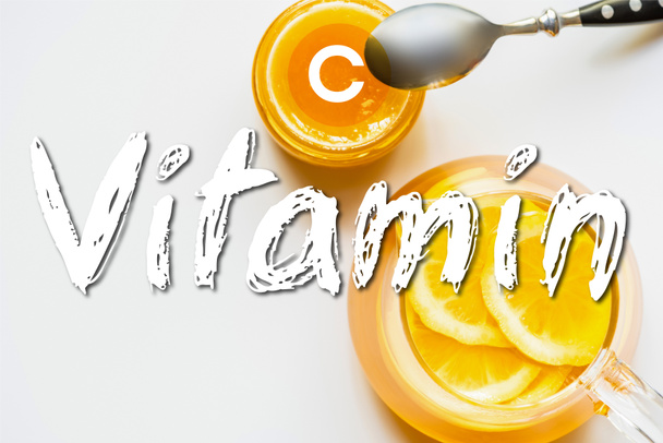 vrchní pohled na horký čaj s citronem v blízkosti medu s lžičkou na bílém pozadí, vitamin C ilustrace - Fotografie, Obrázek