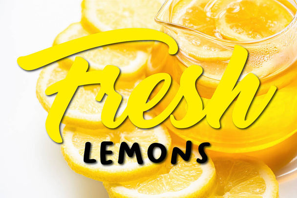 close up view of hot tea in glass teapot with lemon slices on white background, fresh lemons illustration - 写真・画像