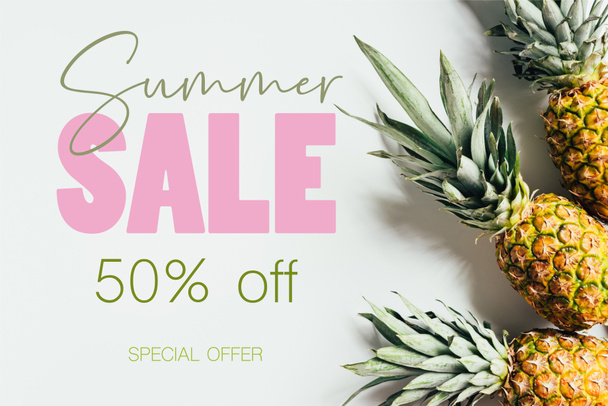 top view of ripe pineapples with green leaves on white background with summer sale illustration - Fotografie, Obrázek