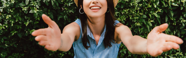 horizontal crop of happy girl with outstretched hands near green bush  - Photo, Image