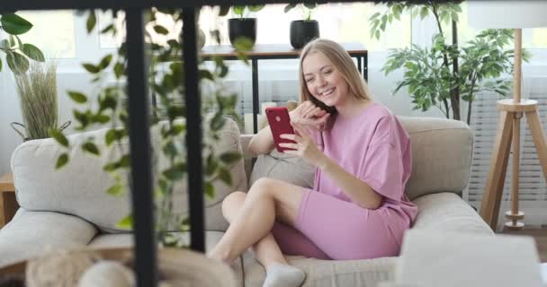Mujer vídeo chat utilizando el teléfono móvil en casa - Imágenes, Vídeo