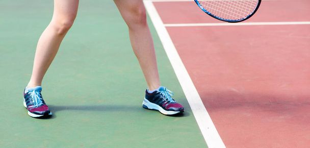Jambes de jeune fille dans un court de tennis fermé avec raquette - Photo, image
