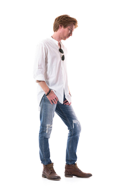 Side view of sad disappointed young casual man looking down with bowed head. Full body length isolated on white background.  - Photo, Image