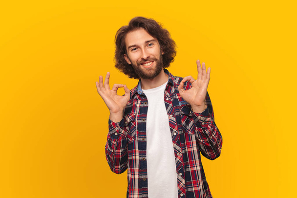 Handsome man with long hair in a shirt smiling shows all is well yellow background. - Foto, Imagen