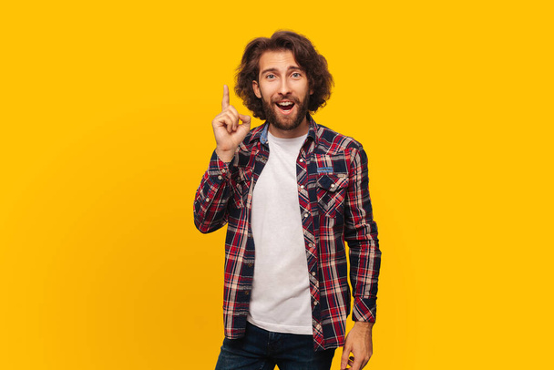 Portrait of a positive handsome man with curly hair and beard who came up with an idea, a man shows his thumb up, looks at the camera - Fotoğraf, Görsel
