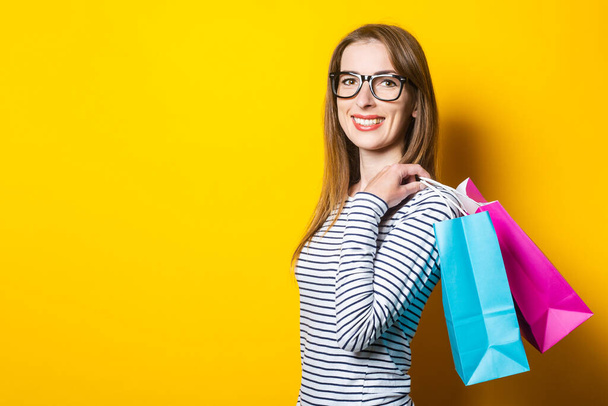 Young happy smiling woman with shopping bags over yellow background. Online shopping. - Foto, Bild