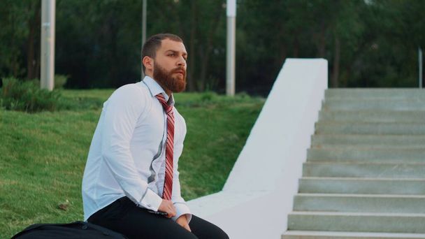 Atractivo hombre de negocios sentado en las escaleras en el parque
 - Foto, imagen