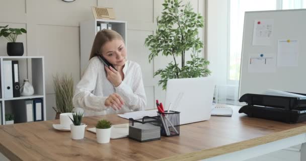 Businesswoman talking on phone and writing notes - Felvétel, videó