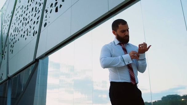 Liikemies valkoisessa paidassa sitomassa solmiota ja katsomassa kameraa - Valokuva, kuva
