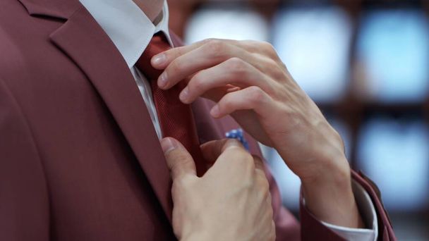 Вид сбоку на молодого бизнесмена, поправляющего галстук
 - Фото, изображение