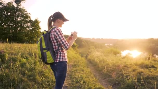 femme touristique avec un sac à dos et une caméra marche à travers une prairie pittoresque. - Séquence, vidéo