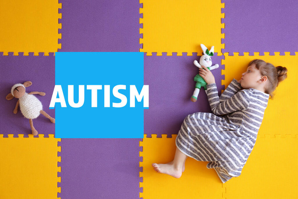 Klein meisje met autistische stoornis liggend op de vloer, bovenaanzicht - Foto, afbeelding