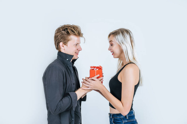 Portret van gelukkig jong stel liefde samen verrassing met geschenkdoos in studio - Foto, afbeelding