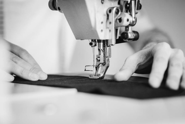 Крупним планом чоловік руками шиє тканину на швейній машині
 - Фото, зображення