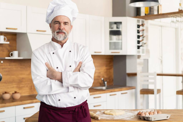 Attractive Caucasian chef standing with arms crossed in a restaurant kitchen - Zdjęcie, obraz