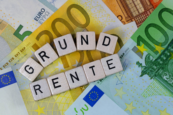 Кубы с буквами с немецким словом Grundrente, аренда земли, на банкнотах
 - Фото, изображение