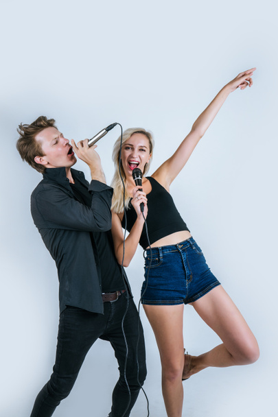 Feliz retrato de pareja sosteniendo micrófono y cantando una canción
 - Foto, Imagen