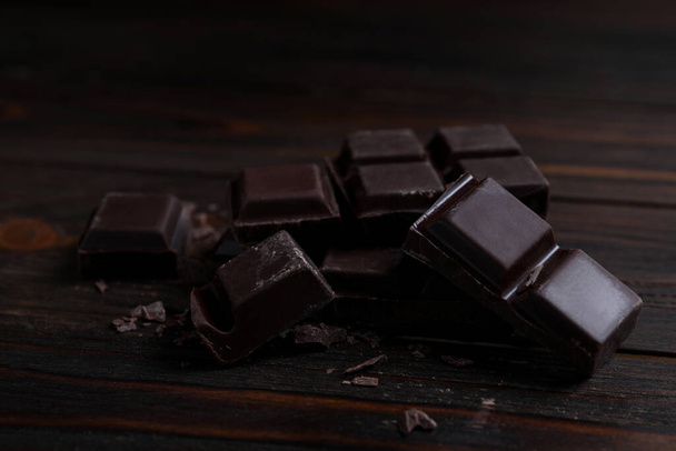 Pieces of delicious dark chocolate on wooden table - Foto, Bild