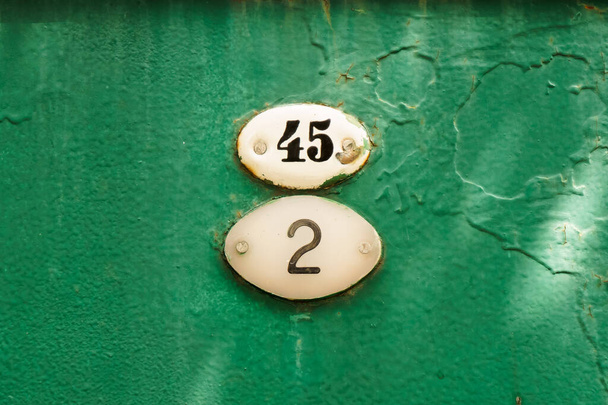 Nummer fünfundvierzig und zweiundvierzig an einem alten rostigen grünen Tor angebracht. - Foto, Bild