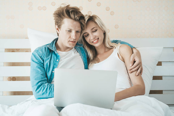 Happy couple Using laptop computer on the bed - Fotó, kép