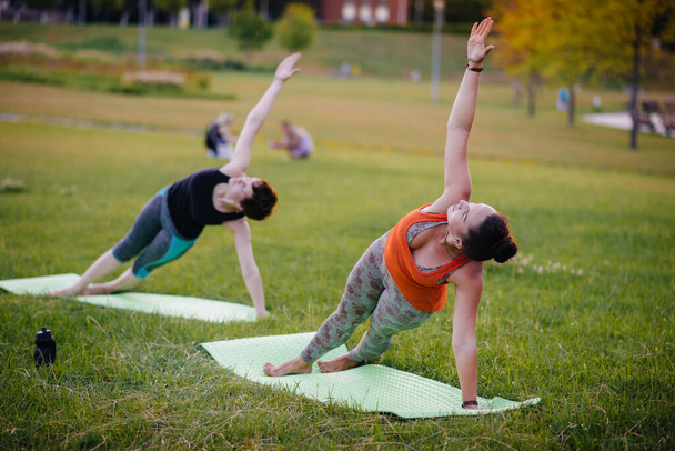 Young girls do yoga outdoors in the Park during sunset. Healthy lifestyle - Φωτογραφία, εικόνα