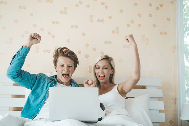 Happy couple watching soccer football on the bed - Фото, зображення