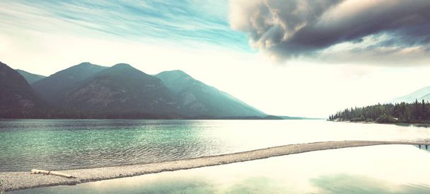 Spokojna scena nad jeziorem w Kanadzie z odbiciem skał w spokojnej wodzie. - Zdjęcie, obraz