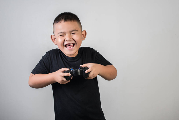 Щасливий хлопчик грає в ігровий комп'ютер з контролером на фотостудії
 - Фото, зображення