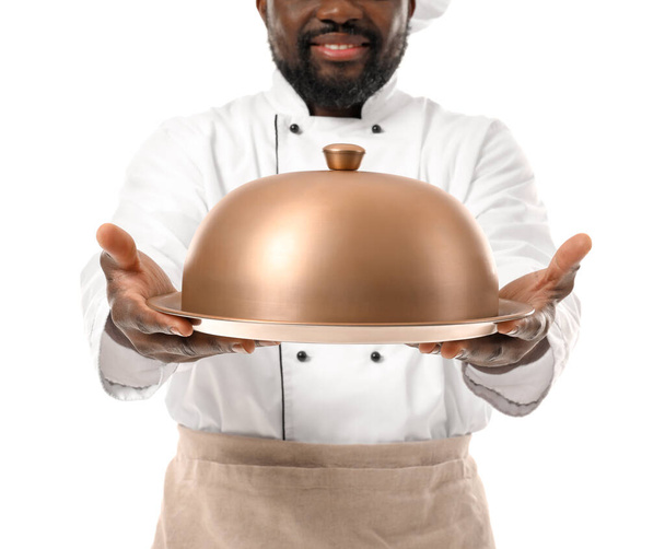 Chef afro-américain masculin avec plateau et cloche sur fond blanc - Photo, image